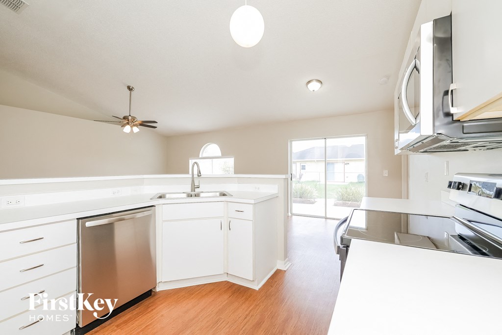 a white kitchen with stainless steel appliances and white counter tops