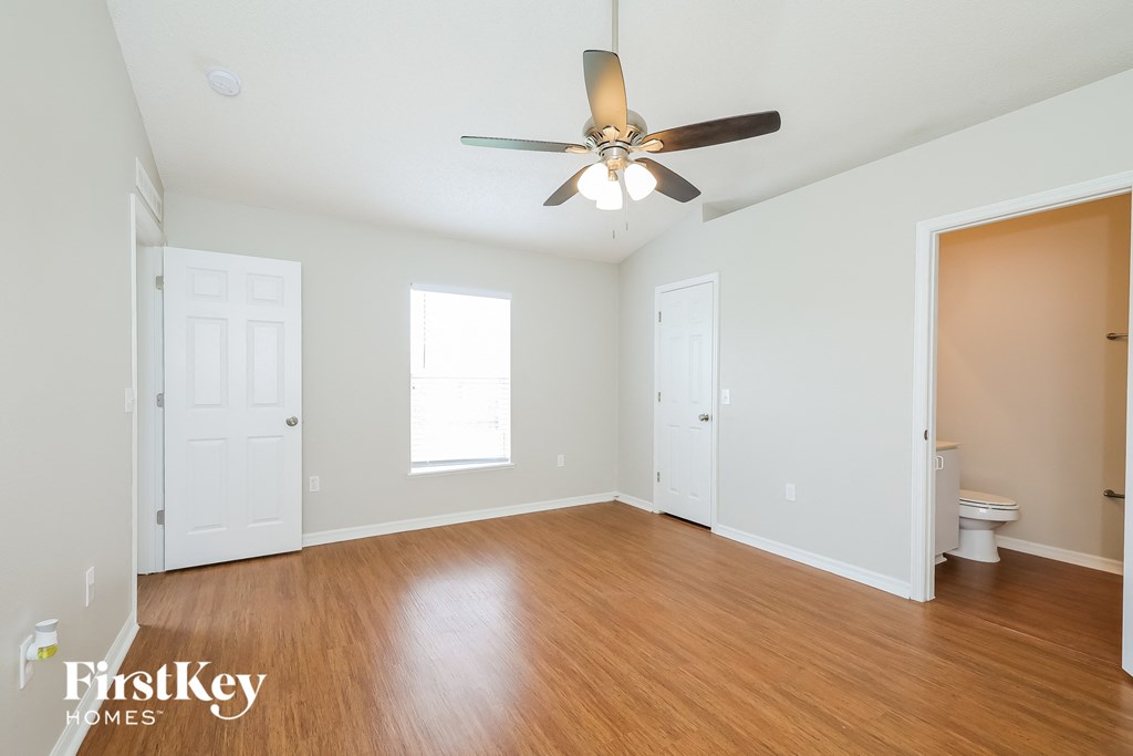 a living room with white walls and a ceiling fan