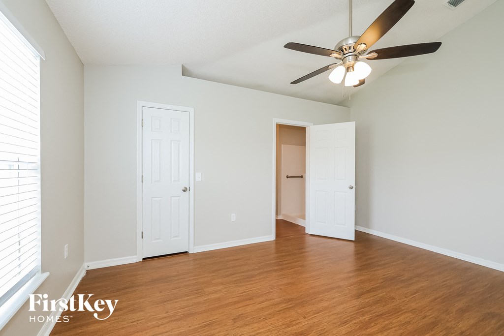 an empty living room with wood floors and a ceiling fan