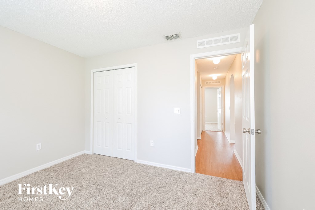 a bedroom with a carpeted floor and a door to a hallway