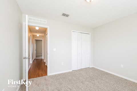 a spacious living room with carpet and a hallway to a bedroom