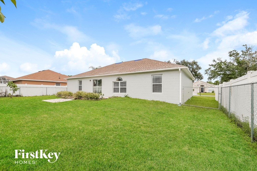 the backyard of a white house with a yard and a fence