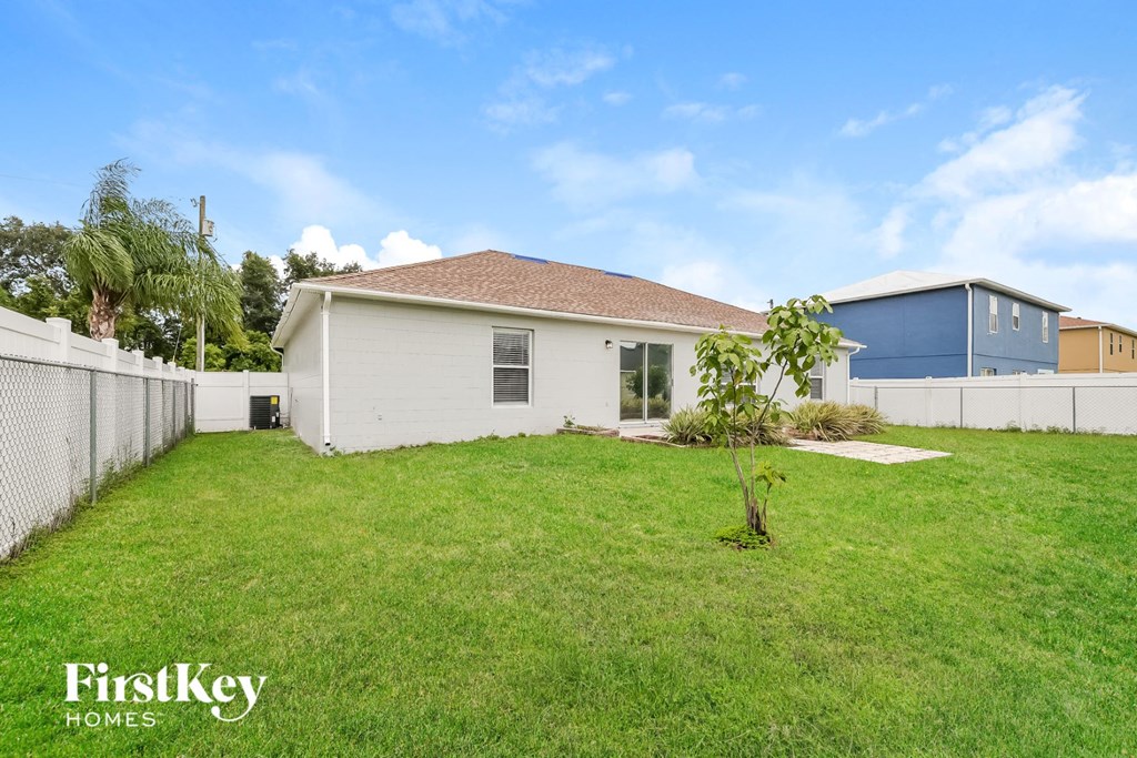 a backyard with a white house and a blue fence