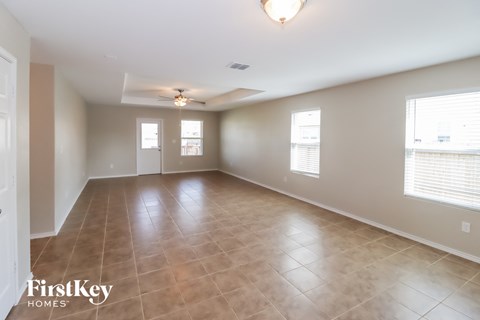 A spacious room with tile flooring and a ceiling fan.