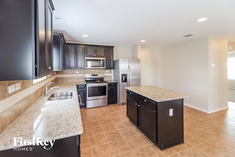 A kitchen with black cabinets and a marble countertop.