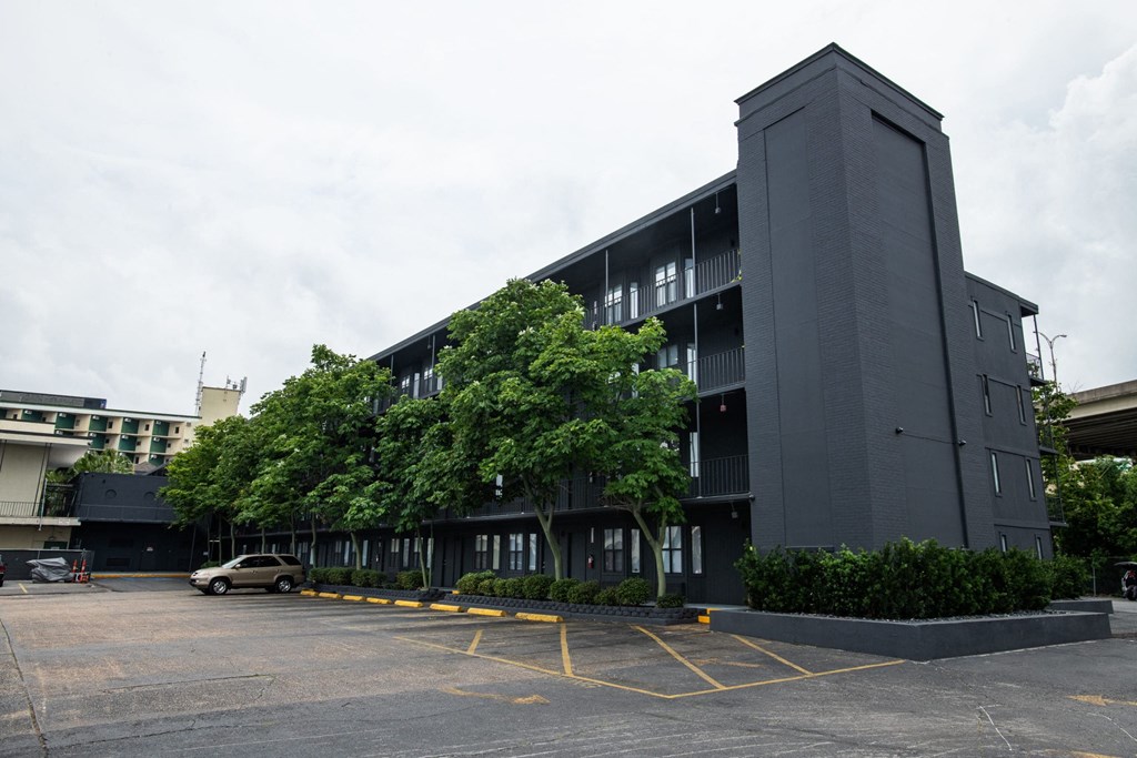 a parking lot in front of a black building with trees