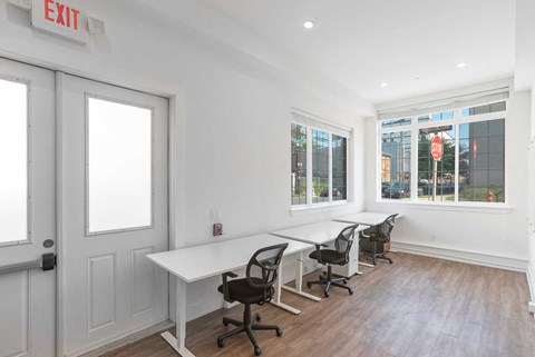 a conference room with white walls and a row of tables and chairs