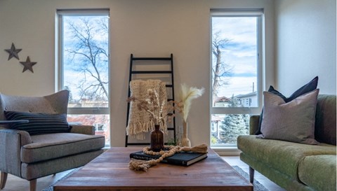 A living room with a grey couch, a wooden table, and a ladder leaning against the wall.