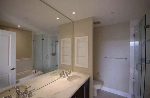 A bathroom with a large mirror, a sink, and a walk-in shower.