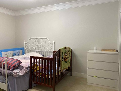 A white bed with a blue headboard and a white dresser with a wooden top.