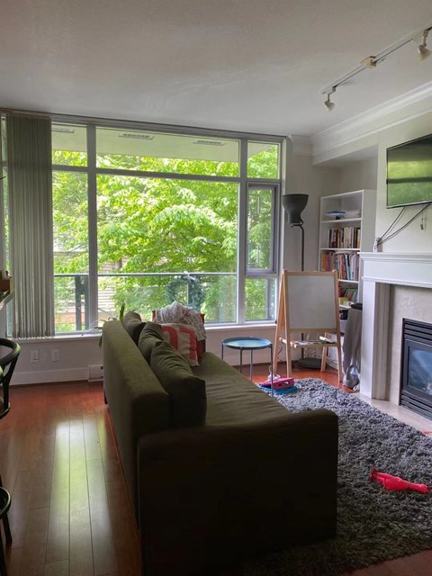A living room with a couch, a chair, a fireplace, and a bookshelf.