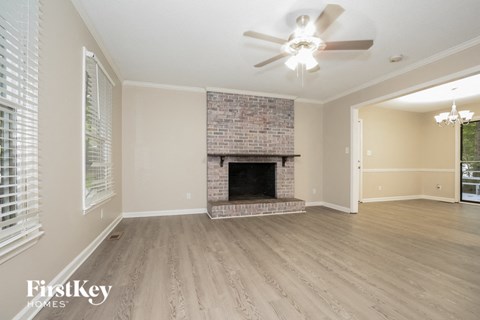 A spacious room with a fireplace and a ceiling fan.