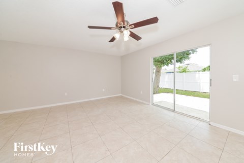 A room with a ceiling fan and sliding glass doors.