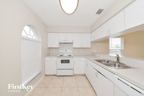 A kitchen with white cabinets and appliances.