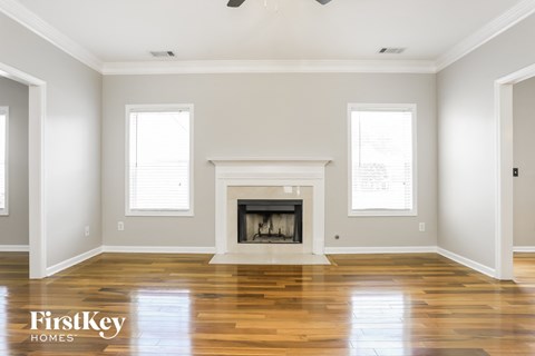 an empty living room with a fireplace and wooden floors
