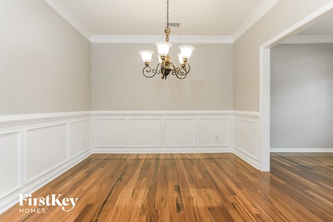 the living room of a house with wood floors and a chandelier