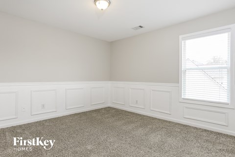 a bedroom with white walls and carpet and a window