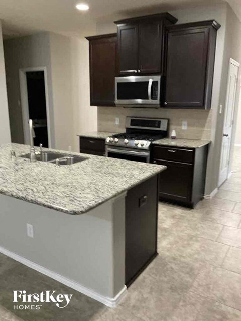 a kitchen with black cabinets and a marble counter top