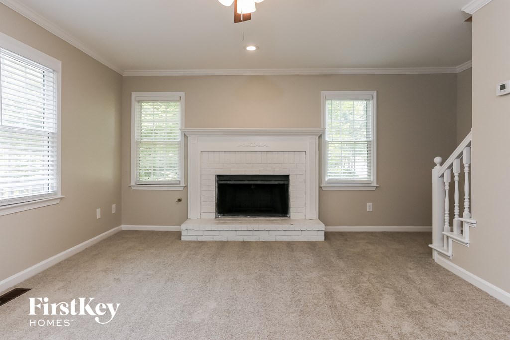 A spacious living room with a fireplace and two windows.