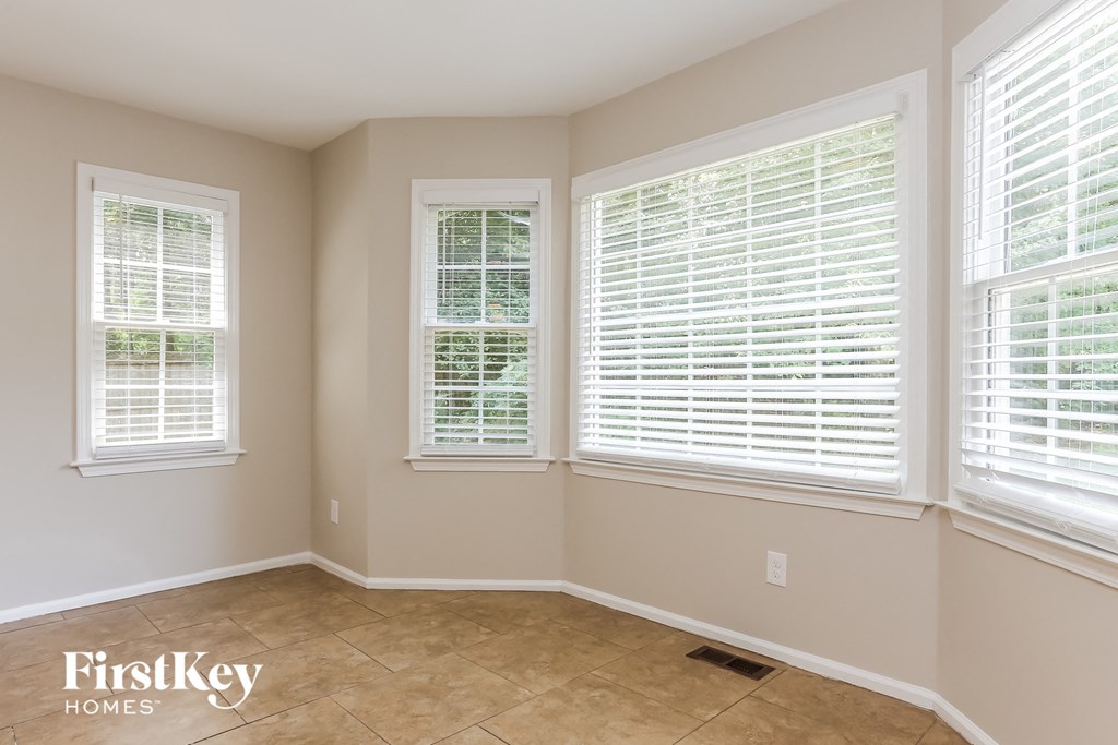 A room with two windows, one with blinds and one with no blinds, with a FirstKey Homes logo on the bottom left.