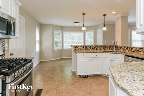 A kitchen with a black stove top oven and a granite counter top.