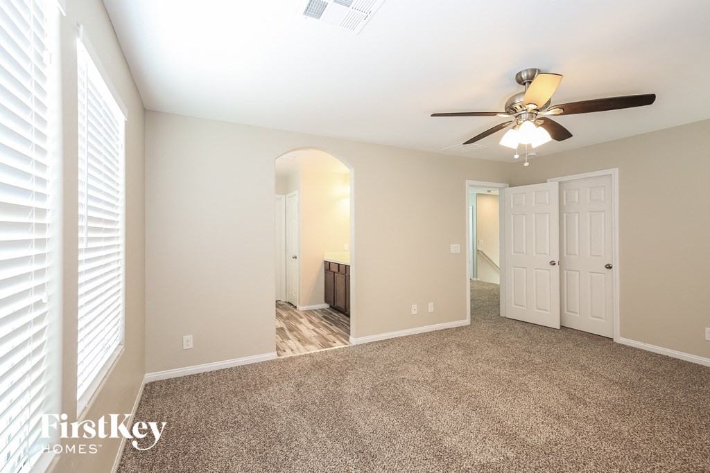 A spacious room with a ceiling fan and carpeted floor.