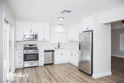a white kitchen with white cabinets and stainless steel appliances