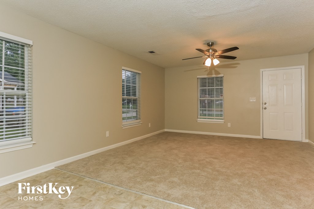 an empty living room with a ceiling fan and a white door