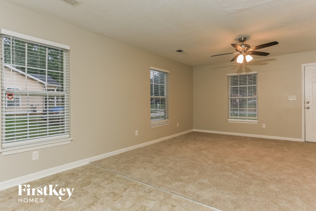 an empty dining room with a ceiling fan and two windows