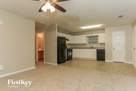 a kitchen with black appliances and white cabinets and a ceiling fan