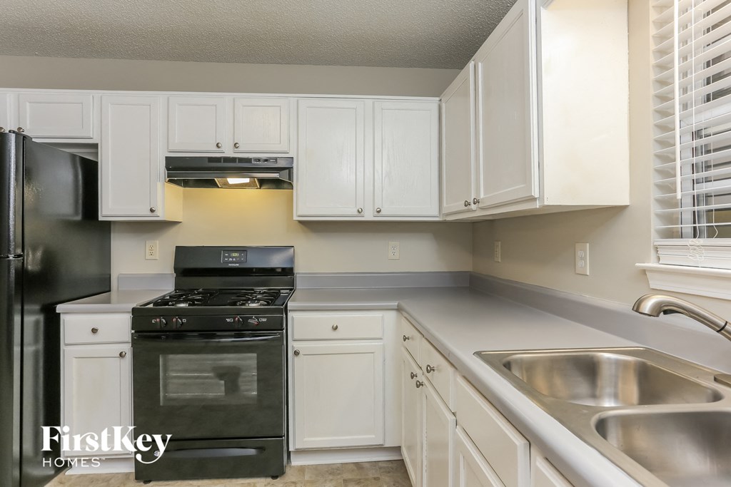 a kitchen with white cabinets and black appliances and a sink