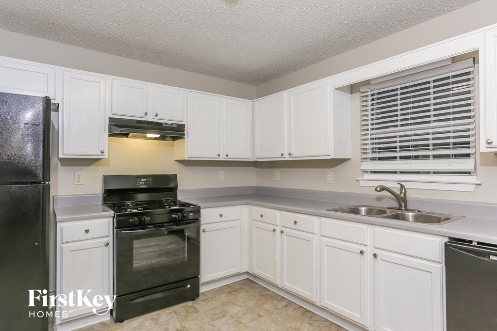 a kitchen with white cabinets and black appliances and a sink