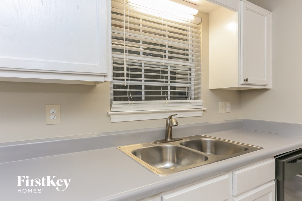a kitchen with white cabinets and a sink and a window