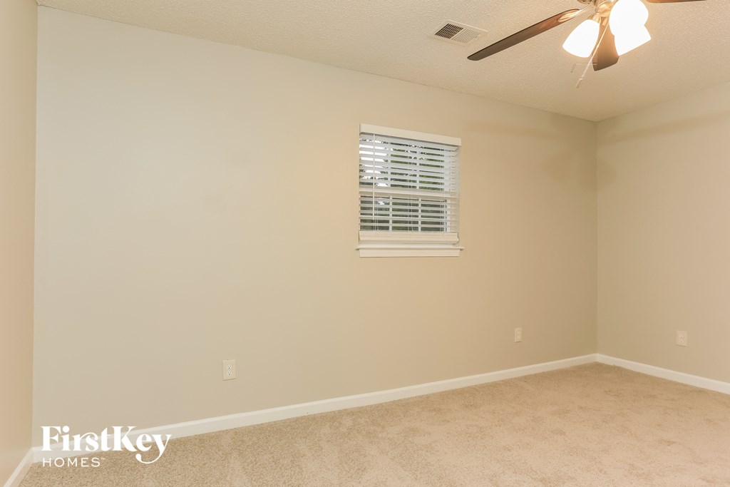 a empty living room with a ceiling fan and a window
