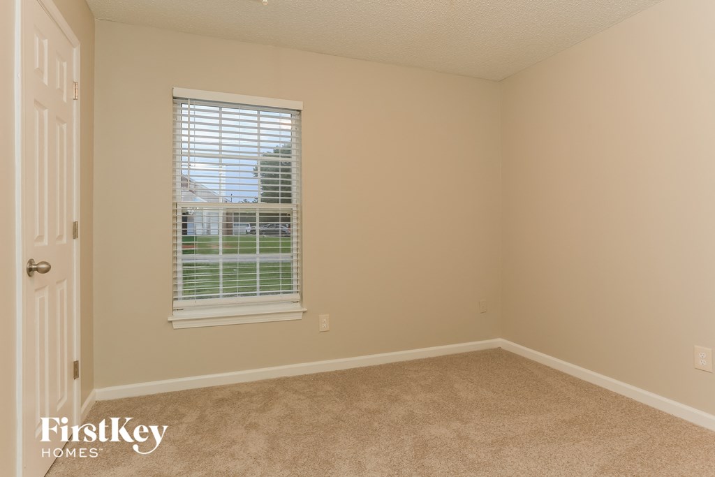 a bedroom with a window and a carpeted floor