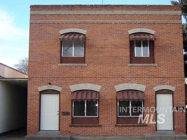 a brick building with three windows and a white door