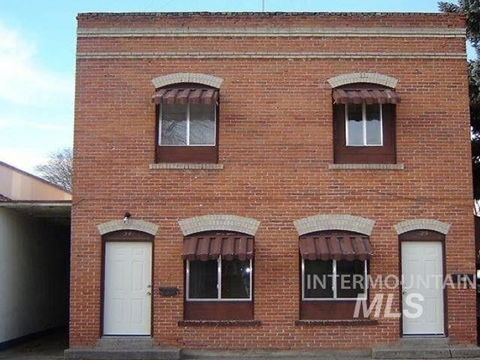 a brick building with three windows and a white door