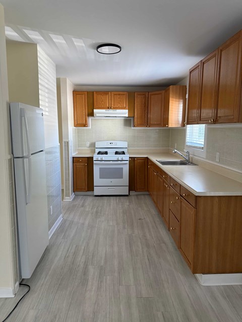 A kitchen with wooden cabinets and a white stove top oven.