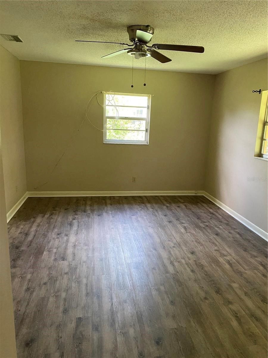 an empty room with wooden floors and a ceiling fan