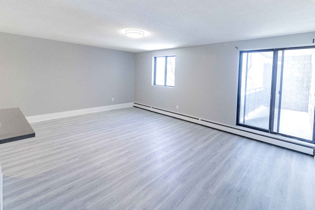 an empty living room with a large window and wood flooring