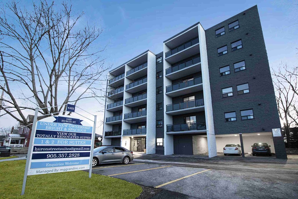 an apartment building with a parking lot and a sign in front of it