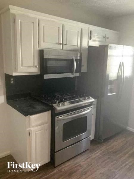 A kitchen with white cabinets and a black countertop.