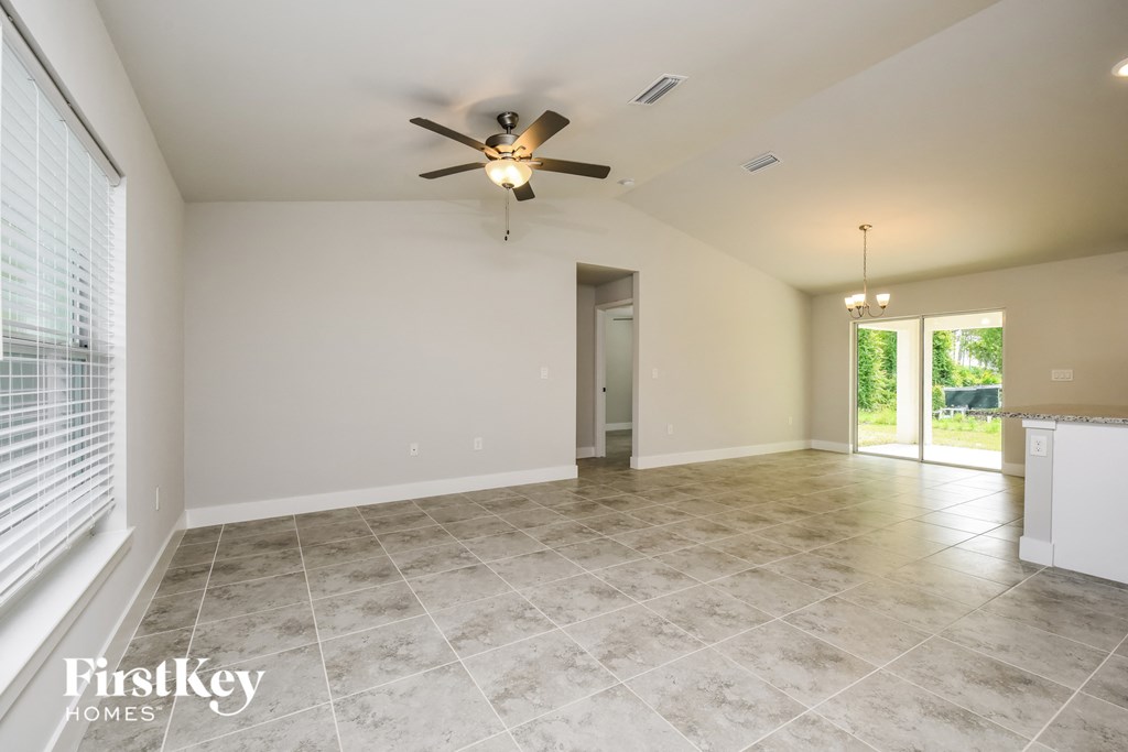 the spacious living room with tile flooring and a ceiling fan