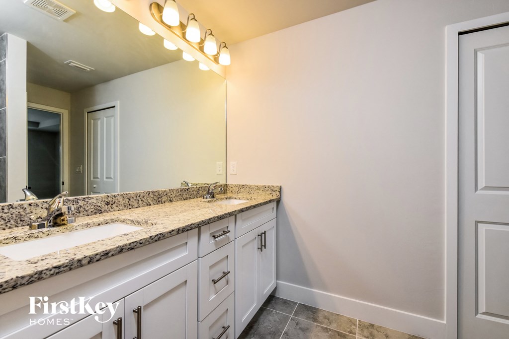 the master bathroom has a large vanity and a large mirror