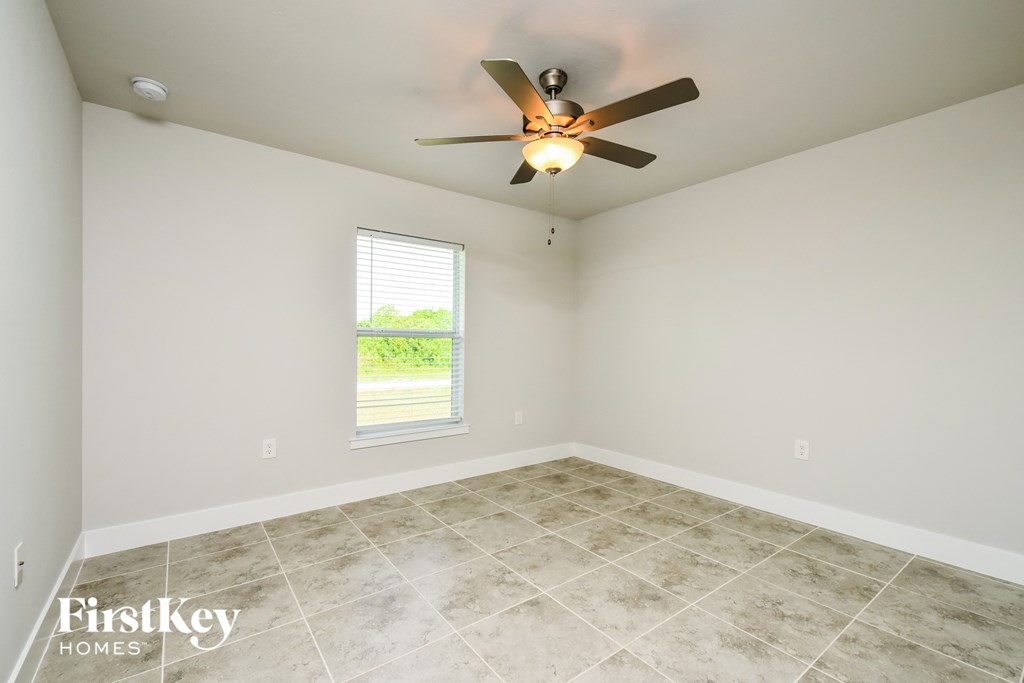 the spacious living room with ceiling fan and tile flooring