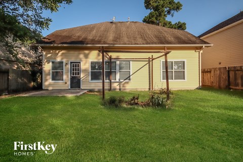 the backyard of a yellow house with a covered porch and grass