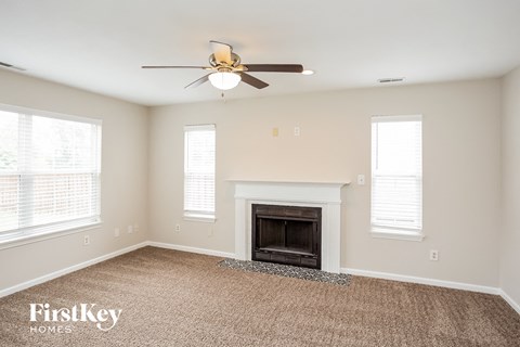 A spacious room with a fireplace and a ceiling fan.