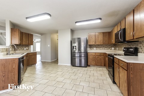 A kitchen with wooden cabinets and a tiled floor.
