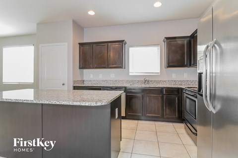 A kitchen with a stainless steel refrigerator and a granite countertop.