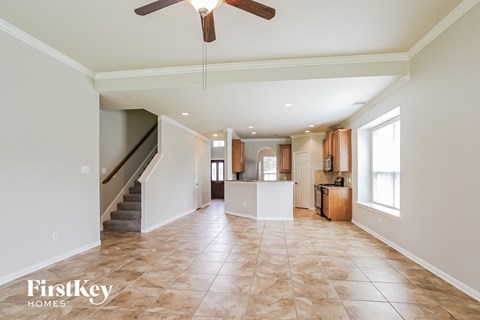 A spacious living room with a staircase and a ceiling fan.